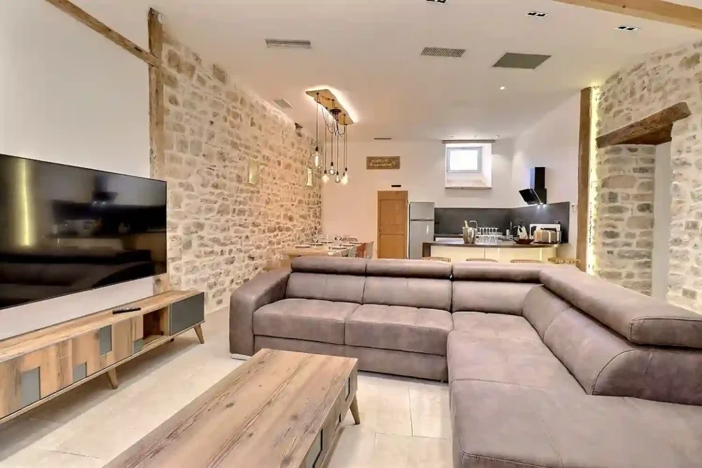 Salon du Gîte Le Figuier à Gras, murs en pierre et TV connectée