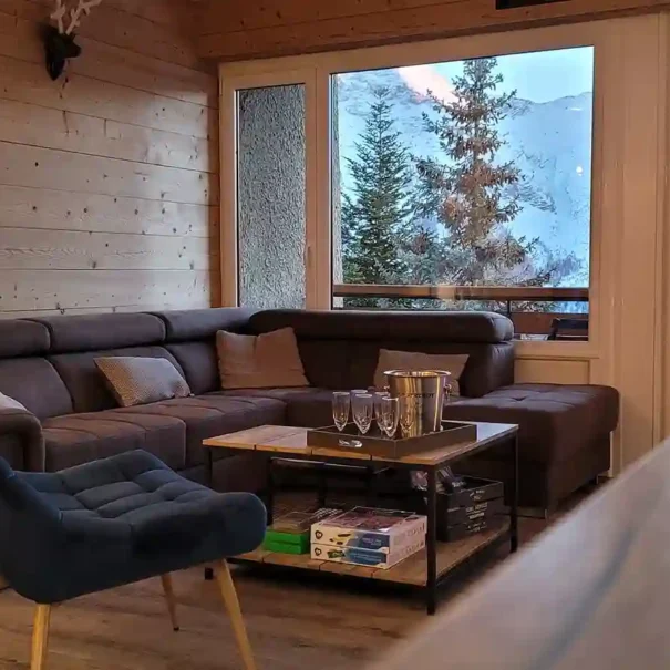 Salon mur bois avec grand canapé et superbe vue montagne dans l'appartement Horizon 1800 à Orcières.