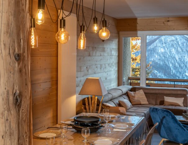 Vieille poutre en bois, luminaire en suspension fait main au dessus de la table en bois dans l'appartement Horizon 1800 à Orcières
