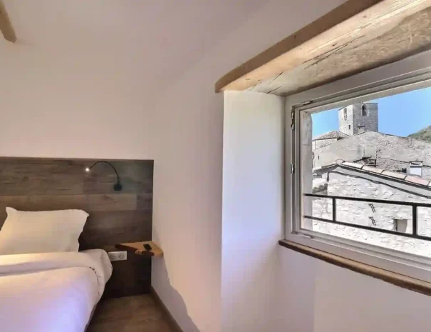 Chambre lumineuse avec lit double et vue sur le clocher de Gras.